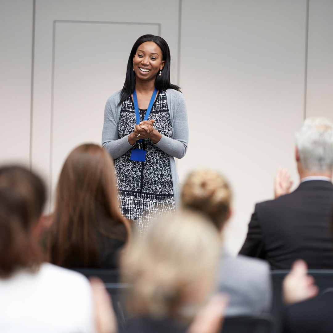 An African American woman in front of an audience ready to give a presentation